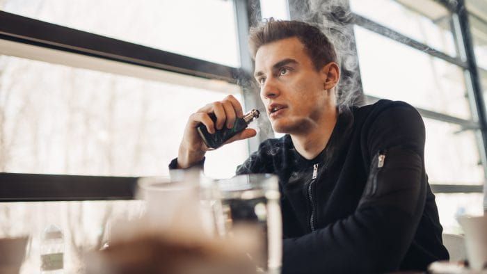 Young man vaping in closed public space.