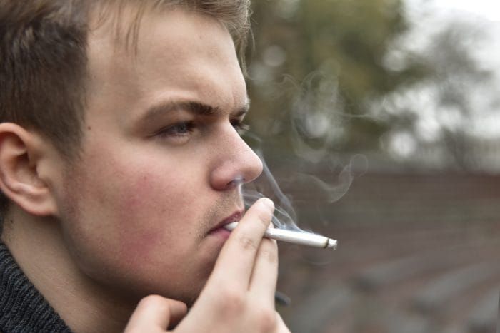 Guy smokes a cigarette outside, portrait, close-up