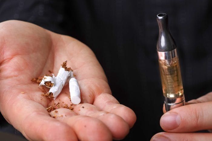 choosing between tobacco cigarette and e-cigarette | crushed tobacco cigarette in hand | electronic cigarette