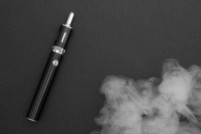 electronic cigarette over a dark background. E-cigarette for vaping. Popular devices of the year - modern vaping device. Stop smoking,start vaping vape