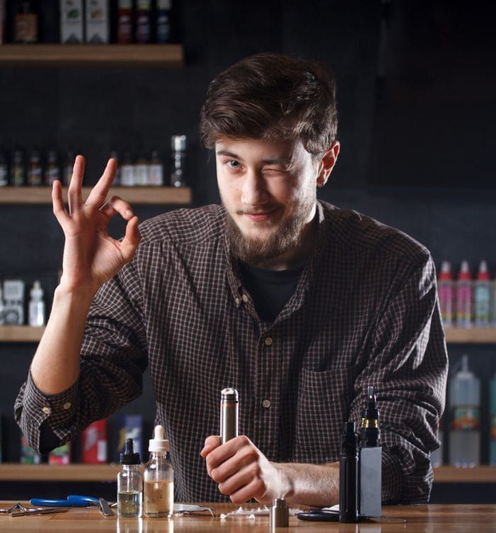 Vape shop. A man is holding a mod in hand and shows "ok"