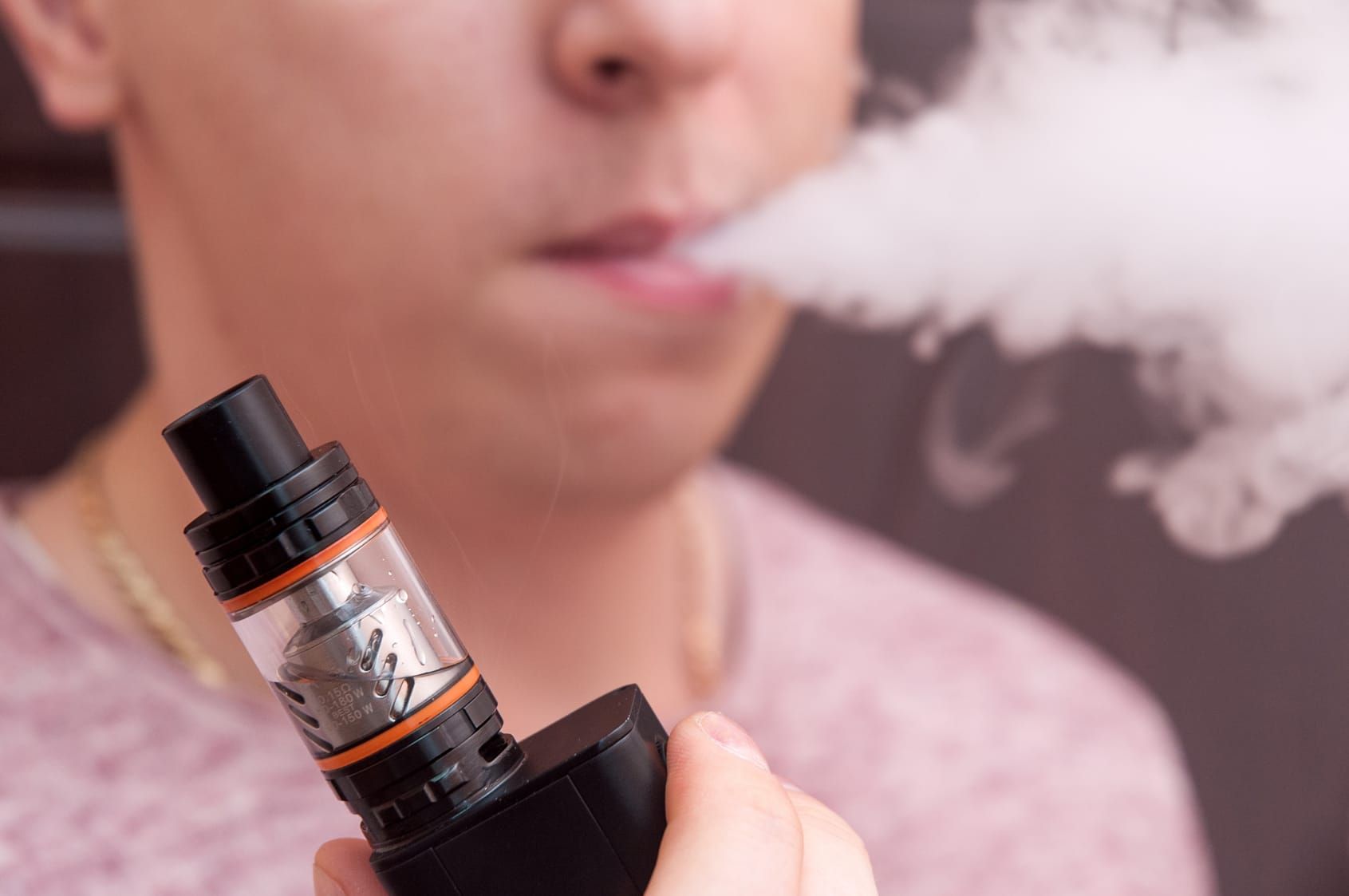Men vaping and releases a cloud of vapor