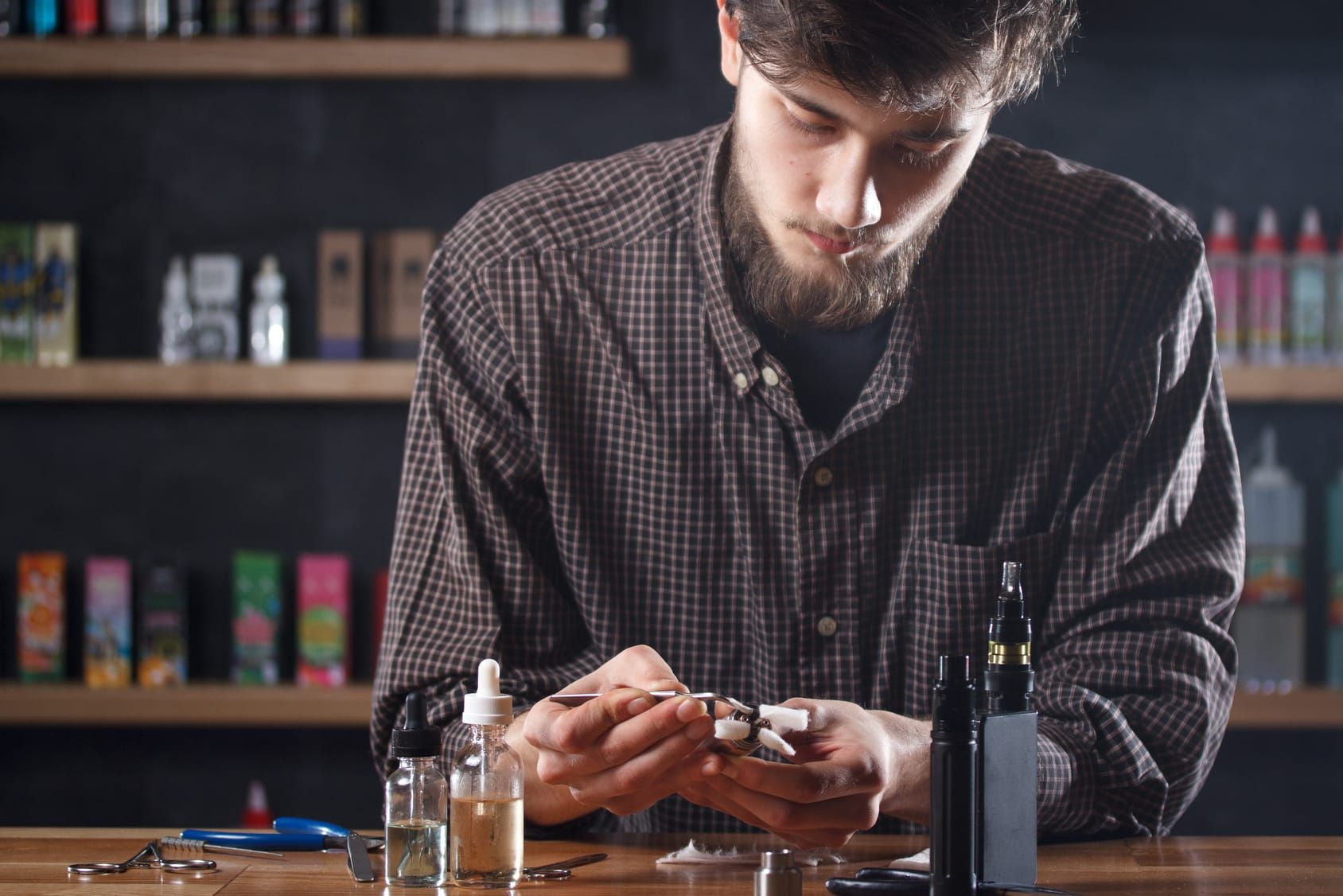 Vape. One man in a vape bar (shop) is repairing e-cigarette | Electric Tobacconist UK