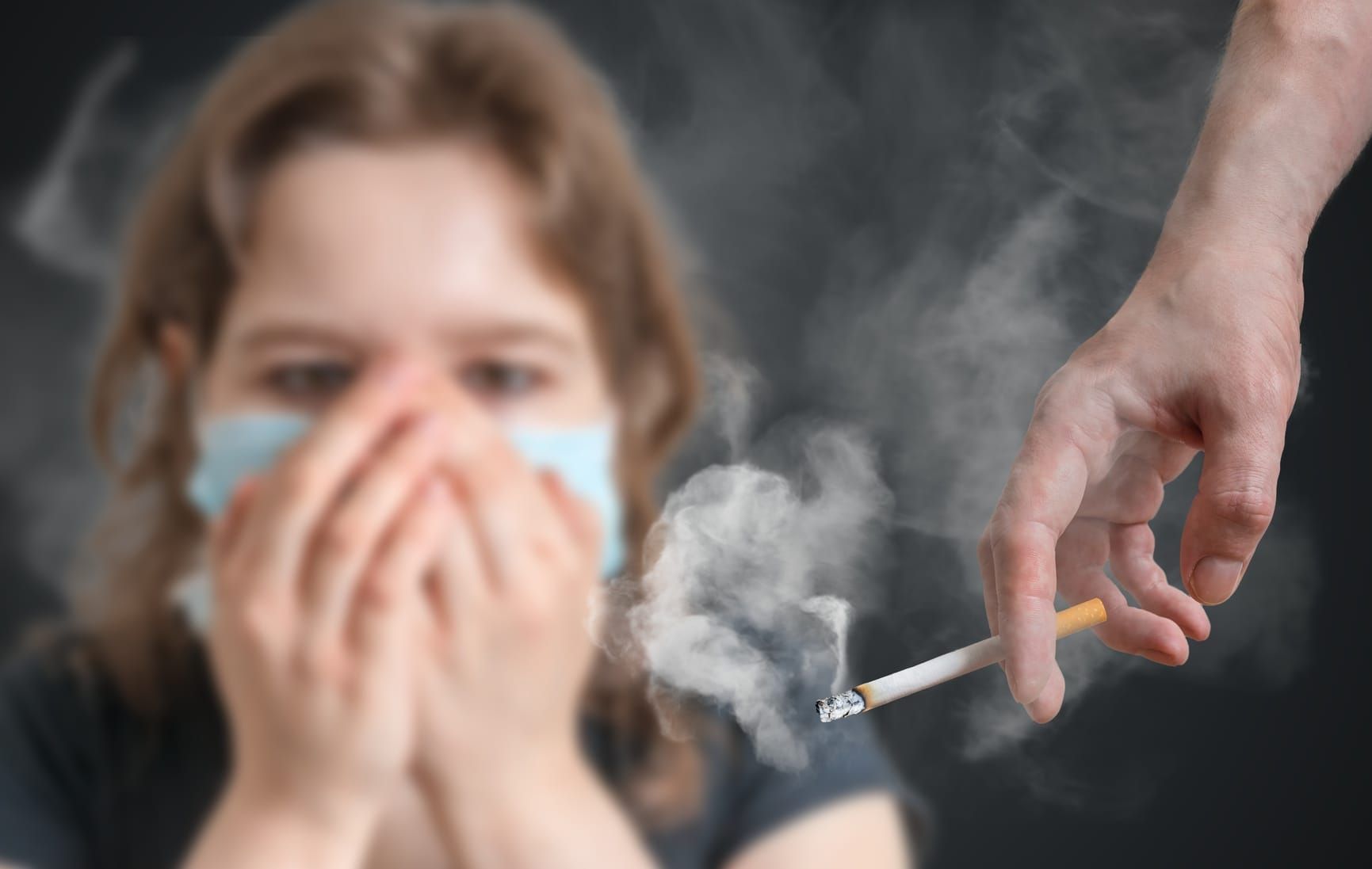 Passive smoking concept. Woman is covering her face from cigarette smoke.