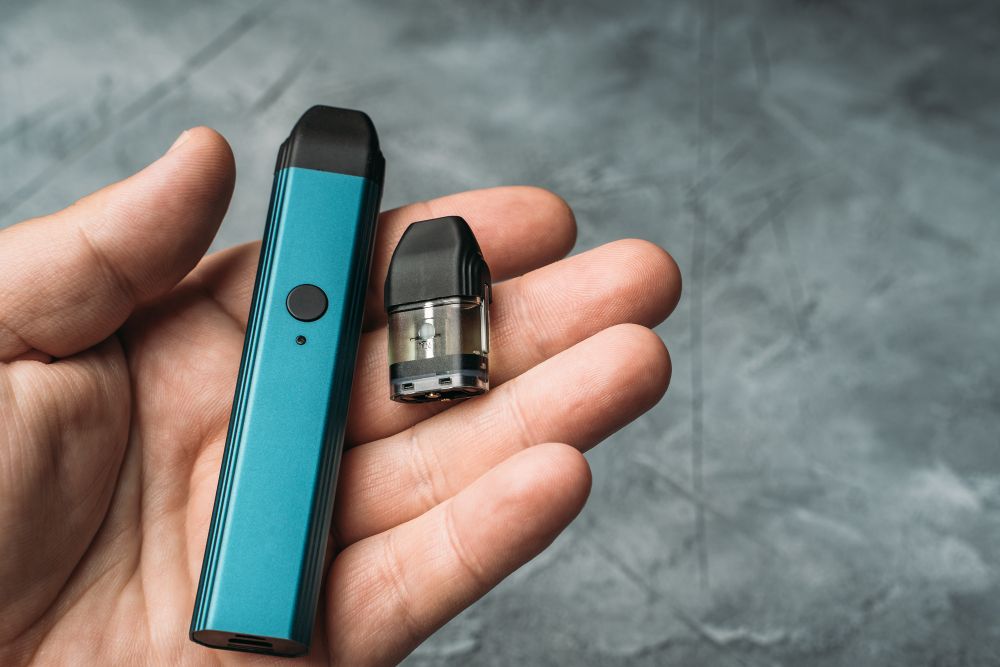 Vape pod in male hand or pod mod with changeable cartridges close up - newest generation of vaping products.