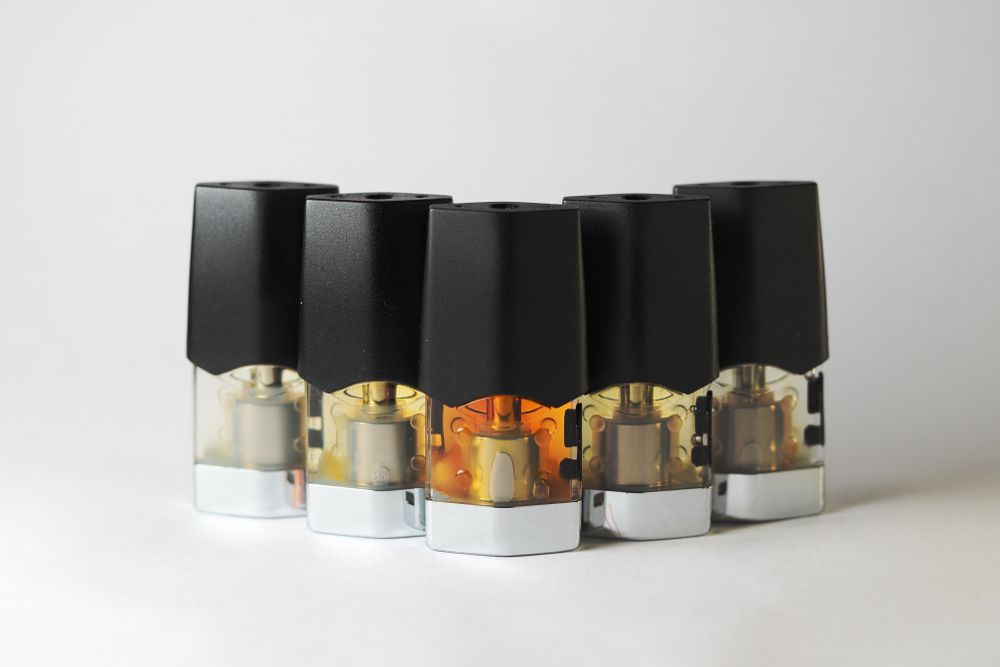 e-juice vape refill pods with liquids of different shades of orange arranged to form a gradient, isolated close up