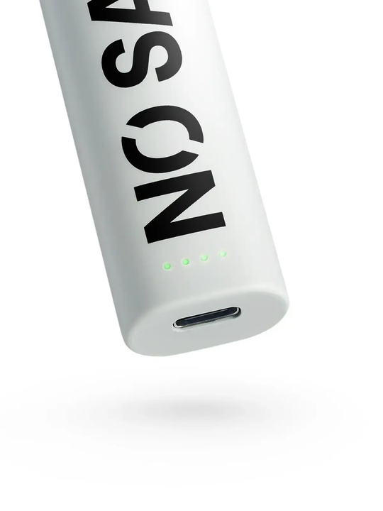 A close up of the base of the NO SAINT vape device, which shows the USB-C charging port and the four LED light indicators, which are lit up in green. Picture has a white background