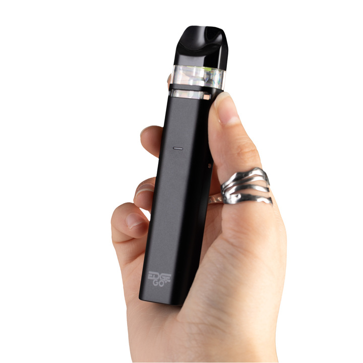 A black Edge Go+ device being held by a human hand, on a white background
