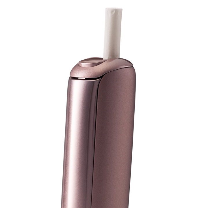 A close up of the Ploom Aura device, in rose gold, with an EVO stick inserted into the chamber. Shown on a white background