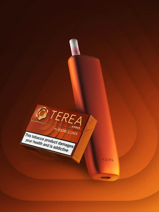 An orange IQOS ILUMA-i One kit with a pack of TEREA Amber sticks floating on a stylised orange background