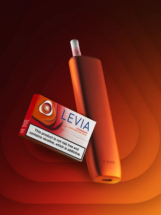 A pack of IQOS LEVIA Strawberry with Watermelon Pearl sticks floating in front of an orange IQOS ILUMA-i One Kit